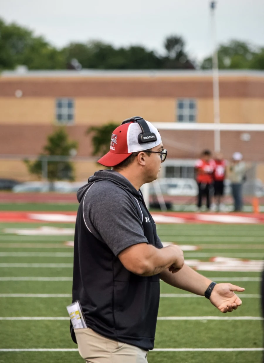 Coach Bartlett wearing a headset and coaching from the sideline.